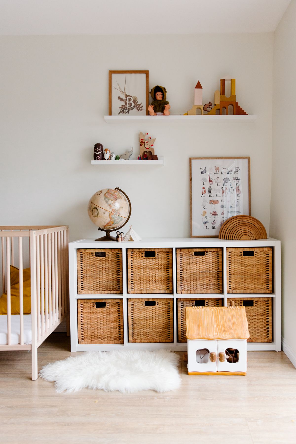 Calm, mood-first kids' bedroom with wooden furniture, storage baskets, and a globe on open shelves